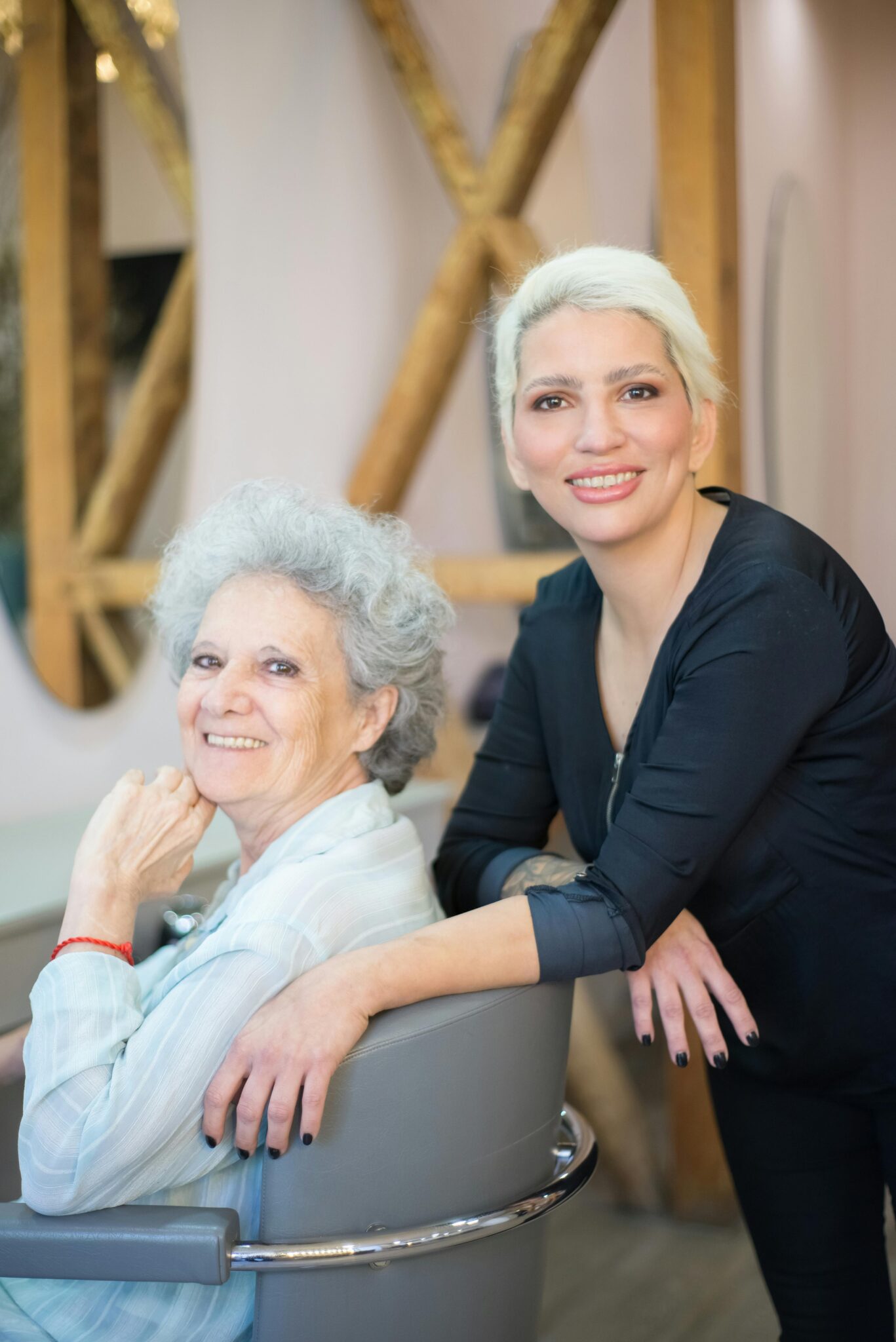 Happy senior woman with hairdresser in salon, smiling brightly.